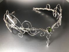 I've hand-forged an alternative bridal tiara featuring elegant scrolling of sterling silver heavy gauged wires. The loops wrap their way around this beautiful, gracefully feminine, and sturdy circlet. I designed it to be multi-layered with twists of vine and leaf work. Each piece and part of this crown is designed, by hand. Each leaf hand-drawn and forged along with the curliques and scrollwork of ivy vine work. This comes with an 8mm round genuine cabochon, or faceted, of your choosing, in the Unique Wedding Crown Headpiece, Whimsical Crown-shaped Jewelry For Weddings, Handmade Teardrop Crown Jewelry For Wedding, Whimsical Sterling Silver Wedding Jewelry, Handmade Silver Crown-shaped Jewelry, Handmade Silver Crown Jewelry, Whimsical Adjustable Wedding Jewelry, Fantasy Adjustable Wedding Jewelry, Adjustable Fantasy Wedding Headpiece