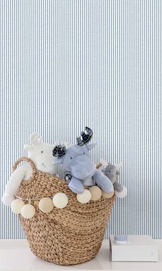 two stuffed animals sitting in a basket next to a wallpapered blue and white background