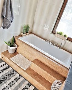 a bathroom with a bathtub, rugs and plants on the counter next to it