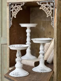 three white candlesticks sitting on top of a wooden table next to an open box