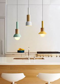 three hanging lights above a kitchen island with stools