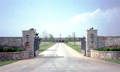 an open driveway leading to a stone fence and gated in area with grass on both sides