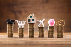 stacks of coins with miniature houses and small toys on top, in front of them