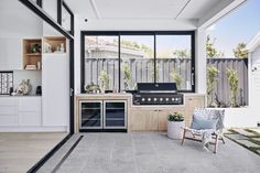 an outdoor kitchen with large windows and grilling area in the middle of the room