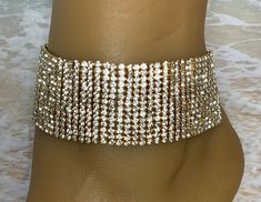 This gold ankle bracelet features a brilliant wide rhinestone band that adds a dramatic touch of elegance to your feet. This piece detaches at the back of the ankle with a lobster claw latch and is size adjustable. Comfortable and versatile, it will lend itself to casual or formal events. My anklets are sold Individually (one per order) and are one size fits most All items are made in a smoke free environment * If there is any issue with your footwear, please let me know so that I can correct it Wedding Anklets With Rhinestones And Crystal, Gold Rhinestone Anklets For Party, Gold Anklets With Rhinestones For Party, Party Gold Anklets With Rhinestones, Gold Rhinestone Party Anklets, Adjustable Gold Crystal Anklets, Elegant Bling Anklets For Party, Gold Party Bracelet Anklets, Elegant Party Anklets With Bling