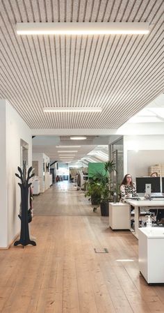 an empty office with wooden floors and white desks on either side of the room