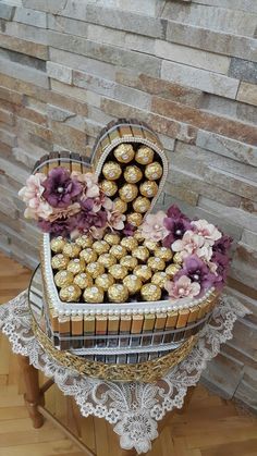 a heart shaped basket filled with chocolates on top of a table next to a brick wall