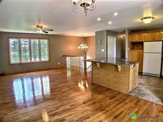 an empty kitchen and living room with wood flooring in the middle of the room