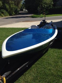 a blue and white boat sitting in the grass