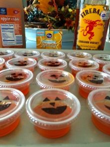 plastic cups filled with different types of desserts on a table next to bottles of orange juice