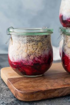 three jars filled with food sitting on top of a wooden cutting board next to each other