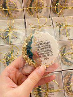 a hand holding an ornament in front of some boxes with gold and blue decorations