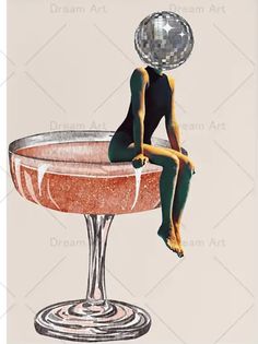 a woman sitting on top of a wine glass with a disco ball above her head