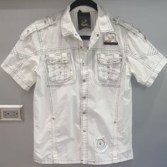 Super Cool & Edgy Distressed White Shirt! Very Well Made And Tailored. They Don't Make Shirts Like That Anymore! Designed With Western-Style Embellishments, Snap Buttons, Logos, Front Pockets, Black Contrast Stitching, And A Relaxed Fit. Versatile, Will Look Amazing With Any Outfit. Very Comfy, Made Of High-Quality Sturdy Yet Breathable 100% Cotton Treated To Create Superb Vintage Look & Washes To Fabric Approx: Pit To Pit 21", Sleeve 8.5", Length 25". Nwot From A Clean, Smoke-Free Home. White T-shirt With Button Closure For Spring, White Cotton T-shirt With Button Closure, White Button-up Summer T-shirt, White Short Sleeve T-shirt With Buttons, White Short Sleeve Tops With Buttons, White Cotton Tops With Button Closure, White Cotton Top With Button Closure, White Cotton Shirt With Button Closure, White Short Sleeve Shirt With Pockets For Spring