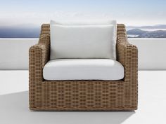 a wicker chair sitting on top of a white floor next to an ocean view