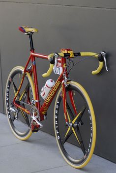 a red and yellow bicycle leaning against a wall