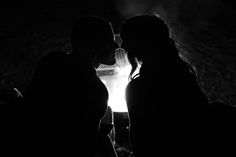 black and white photo of two people in the dark with their faces close to each other