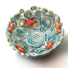 a bowl that has fish in it on a white surface with blue and orange swirls