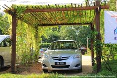 two cars parked in front of a wooden pergolated area with an advertisement on the side