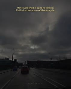 a car driving down a street at night with a sky full of clouds above it