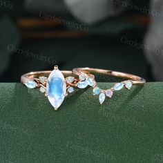 two gold rings with blue topazte and opal stones on green velvet surface