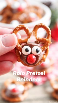 a hand holding up a pretzel shaped like a reindeer with eyes and nose