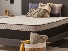 a bed that has some pillows on it and a basket in front of the bed