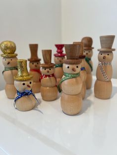 small wooden snowmen with hats and scarves on their heads are lined up in a row