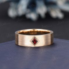 a gold ring with a red diamond in the center