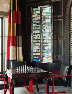 a room with chairs and a table in front of a window filled with glass bottles