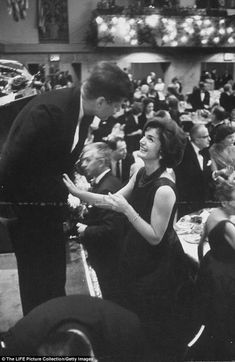 black and white photograph of people in formal wear talking to each other at an event