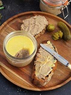 two slices of bread on a wooden plate with mustard and pickles next to it