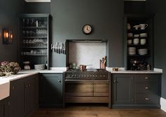 a kitchen with dark green walls and wooden flooring, an old fashioned stove is in the center