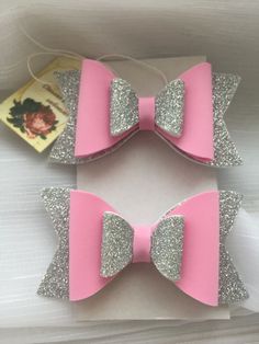 two pink and silver bows with glitter on them