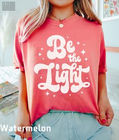 "PRODUCTION TIME: 1-3 days (Usually 2 days) SHIPPING TIME: 2-5 days (Usually 3 days) 👕PRODUCT DESCRIPTION👕 Illuminate your path and uplift those around you with our \"Be the light\" t-shirt, inspired by Matthew 5:14. Spread love and positivity with this colorful Jesus shirt, designed for those who want to make a difference in the world. Our Christian T-Shirt is not only a must-have but also a great religious gift and bible verse shirt that reminds you to love like Jesus. Show your faith wherev Inspirational Pink Cotton T-shirt, Cute Red Shirt With Letter Print, Inspirational Pink Tops With Text Print, Inspirational Pink Crew Neck Top, Pink Cotton Inspirational T-shirt, Inspirational Pink T-shirt With Text Print, Bridesmaid Bachelorette, Bridesmaid Shirt, Shirts Trendy