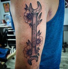 a tattoo with a wrench and flowers on it