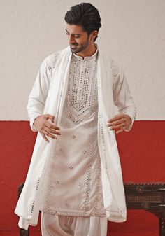 Elevate your style with White Embroidered mirror Kurta. Crafted from georgette, the classic white kurta features intricate hand embroidery and real mirror work, adding a touch of sophistication. Completed with a same-color embroidered dupatta and matching pants. Perfect for Sangeet, Mehendi, Haldi, or as a wedding guest outfit. Composition : Kurta, Patiyala & Dupatta : Viscose Georgette Care: Dry Clean Only and Vacuum Storage This product can be customized for sleeves, length and colour Delivery Unstitched Off White Kurta With Mirror Work, Designer Off White Kurta With Mirror Work, Off White Mirror Work Kurta For Designer Wear, Designer White Sherwani With Mirror Work, Off White Kurta With Mirror Work For Eid, Off White Mirror Work Kurta For Eid, White Semi-stitched Sherwani With Mirror Work, Festive Off White Kurta With Mirror Work, Festive Off-white Kurta With Mirror Work