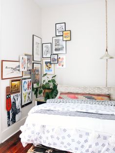 a bed sitting in a bedroom next to a white wall with pictures on the walls