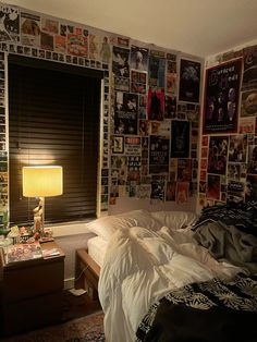 a bedroom with posters on the wall and a bed in front of a table lamp