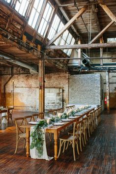 a long table set up in the middle of a room with wooden floors and exposed ceilings