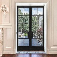 an open glass door in a white room with wood flooring and marble wall decor