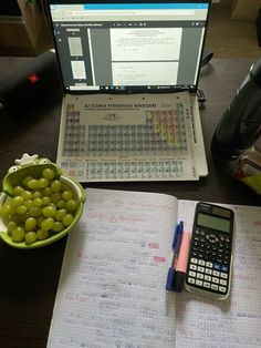 a laptop computer sitting on top of a desk next to a notebook and calculator