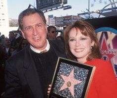 a man and woman standing next to each other in front of a star on the hollywood walk of fame