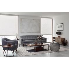 a living room filled with furniture next to large window covered in shades of white and grey