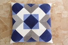 a blue and white pillow on the floor with an interesting design that is made out of felt