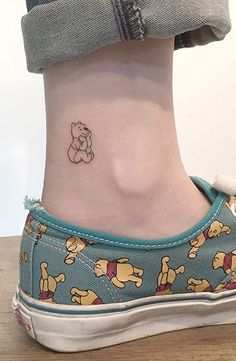 a woman's foot with a small cartoon character tattoo on the side of her ankle