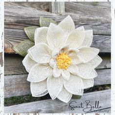 a white flower with yellow center sitting on top of a wooden fence