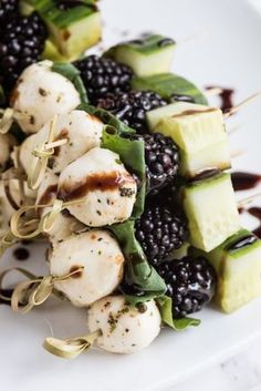 chicken and blackberries skewers with dressing on a white plate, ready to be eaten