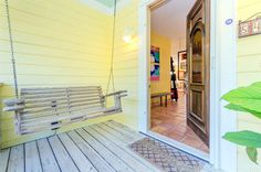 a porch swing sitting on top of a wooden floor next to a door and potted plant