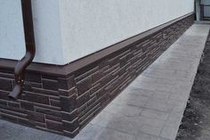 the corner of a building with a brick wall and brown metal hand rail on it